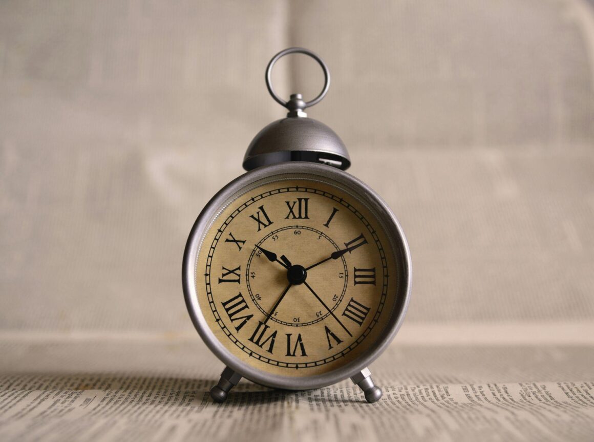 Grey alarm clock on a desk displaying the time